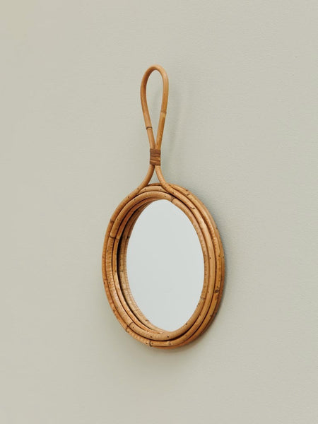 Espejo de ratán natural estilo boho colgado en la pared