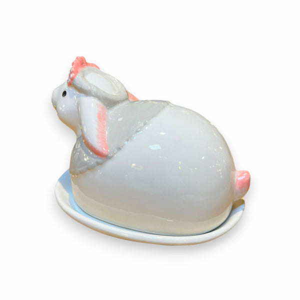 Parte posterior de mantequillera de cerámica con forma de conejo, con detalles en rosa y acabado brillante