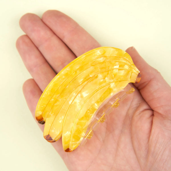 pinza para el pelo bananas Coucou Suzette sostenida en la mano para mostrar tamaño real