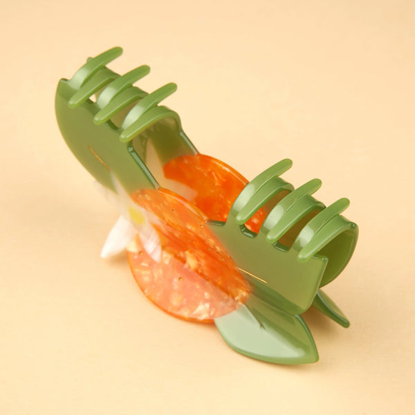 Detalle lateral de la pinza flor de naranjo Coucou Suzette sobre fondo beige.