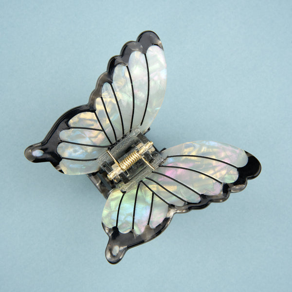 Pinza de mariposa blanca abierta en fondo azul - alas nacaradas y diseño elegante