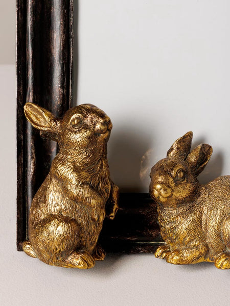 Detalle de conejos dorados decorativos en marco de fotos negro envejecido