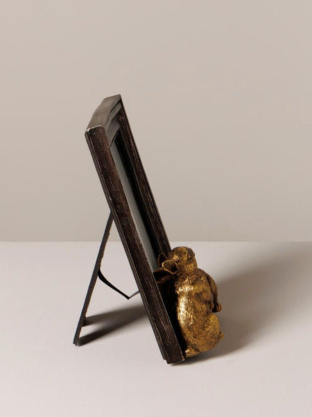 Vista lateral de marco de fotos negro con conejos dorados