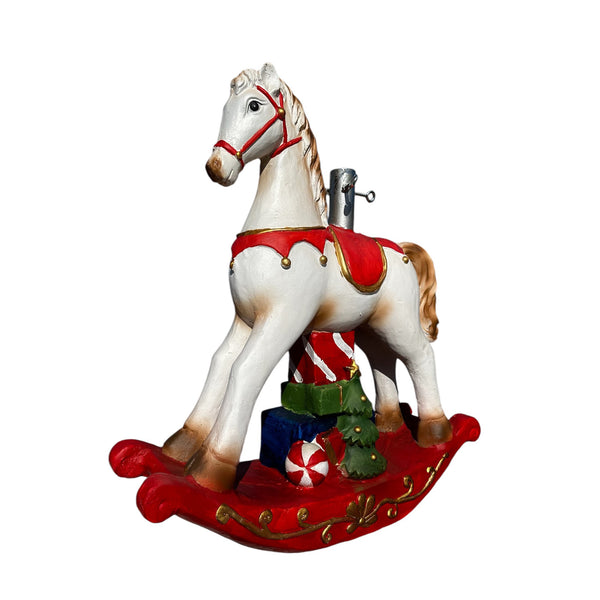 caballo balancín de Navidad blanco y rojo junto al árbol