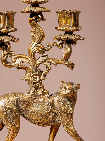 Detalle de candelabro con cuerpo de leopardo dorado y ramas ornamentales en acabado envejecido