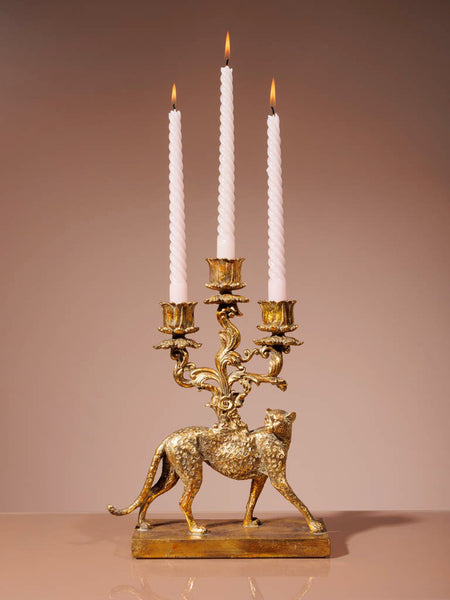 Candelabro dorado decorativo con velas blancas encendidas sobre fondo cálido
