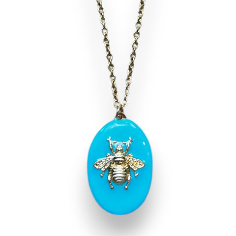 Colgante artesanal mexicano con abeja dorada sobre fondo azul turquesa