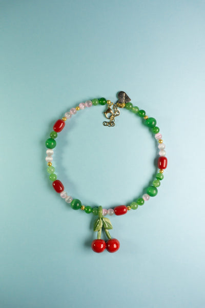 Collar de bisutería italiana con detalle frutal en fondo azul