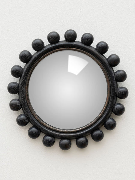 Espejo redondo convexo negro colgado en pared con diseño decorativo elegante.