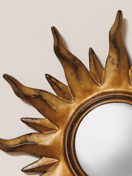 detalle de espejo convexo dorado con rayos solares decorativos