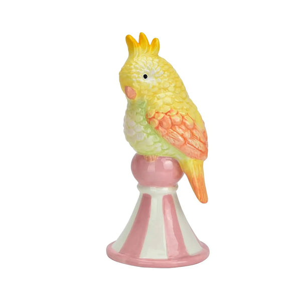 Figurita Loro Amarillo de cerámica esmaltada con plumaje amarillo, alas coral y pedestal rosa y blanco.
