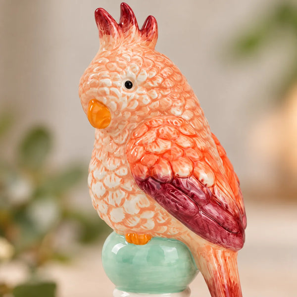 Detalle del plumaje en relieve de la Figurita Loro Rosa de cerámica en tonos coral y granate.