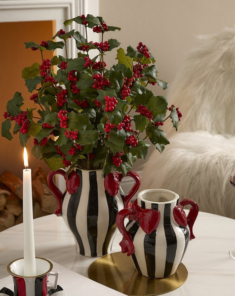 jarrón de cerámica con flores de acebo en decoración navideña