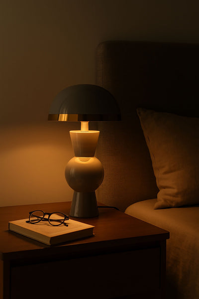 Lámpara seta gris encendida sobre mesita de noche creando una iluminación cálida en dormitorio.