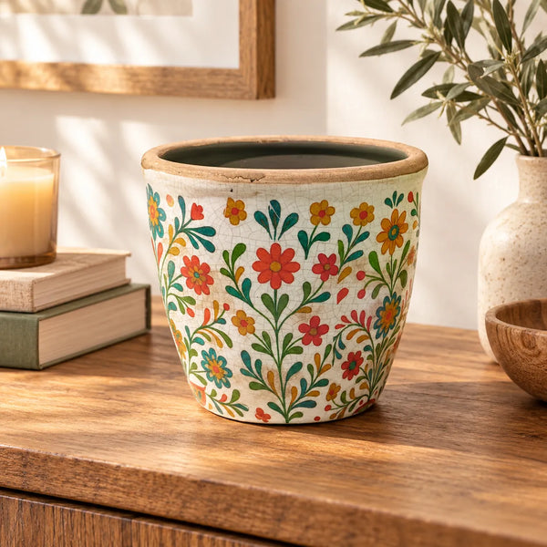 Macetero floral craquelado sobre mueble de madera en ambiente de decoración cálida y natural.