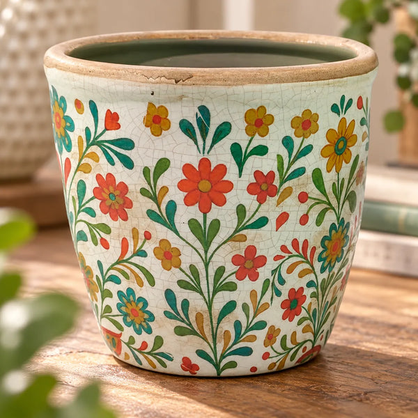 Primer plano de macetero vintage de cerámica con flores multicolor y acabado envejecido.