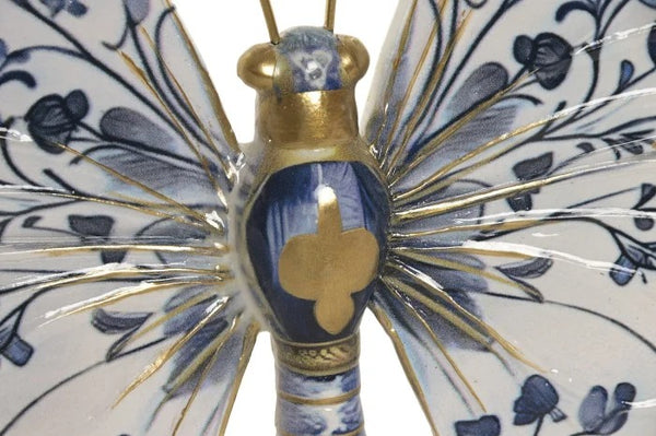 Detalle del cuerpo de mariposa de resina azul y blanca con acabados dorados