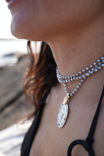 Mujer luciendo collar de cristal gris con medalla