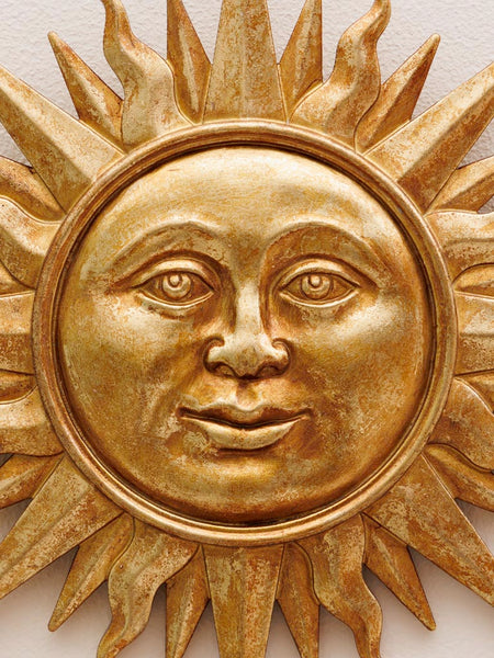 Detalle facial de sol decorativo dorado artesanal