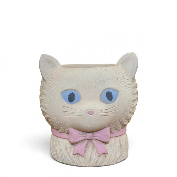 Mini macetero gato de cerámica mate color crema con ojos azules y lazo rosa, vista frontal.