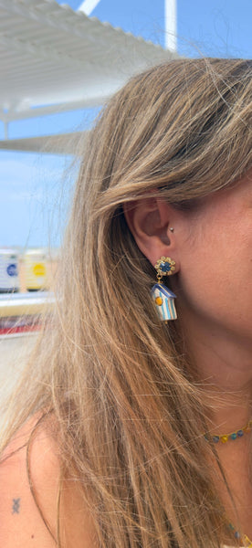 Mujer luciendo pendientes de casetas de playa de Gijón elaborados en cerámica artesanal italiana y Swarovski.