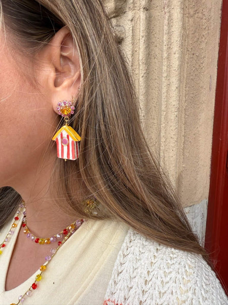 Mujer luciendo pendientes inspirados en las casetas de playa de Gijón elaborados en cerámica y Swarovski.