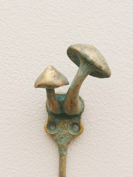 Detalle de setas en relieve en perchero de metal envejecido con acabado verde