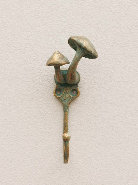Vista frontal de perchero de pared con diseño de setas en metal con pátina verde