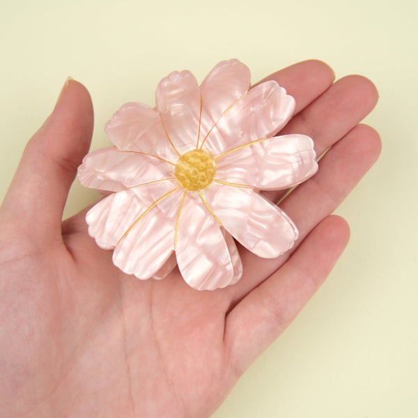 Pinza de pelo flor rosa Cosmos Coucou Suzette sostenida en una mano