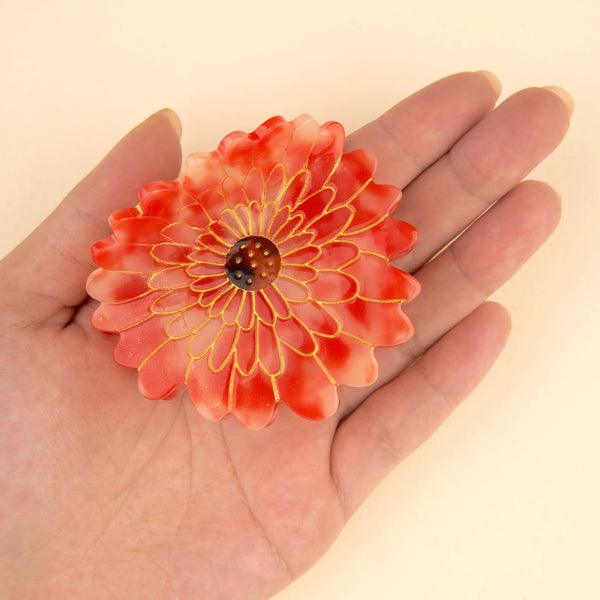 Tamaño real pinza dalia en mano sobre fondo beige