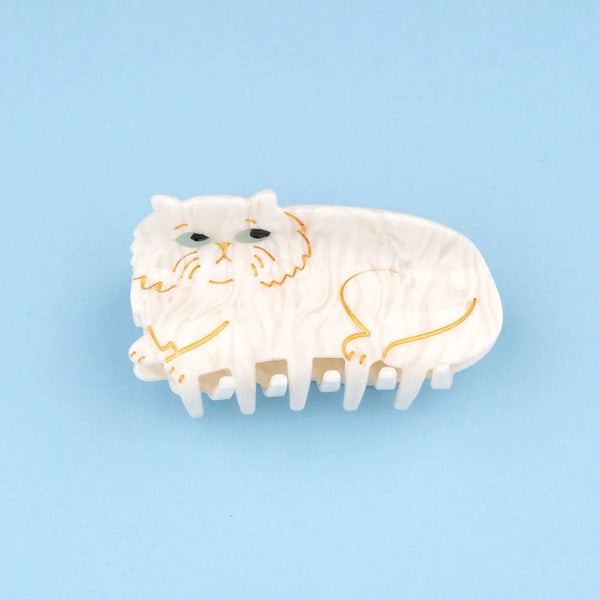 Pinza de pelo con forma de gato persa blanco sobre fondo azul, vista frontal del diseño.