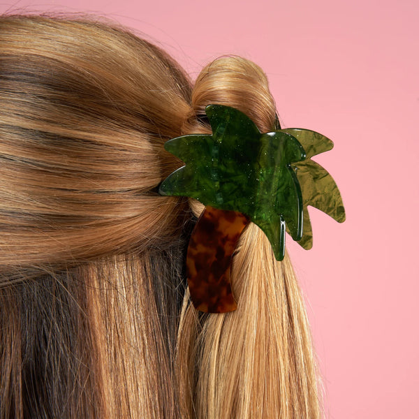 Pinza para el pelo con forma de palmera Coucou Suzette colocada en una coleta sobre fondo rosa.