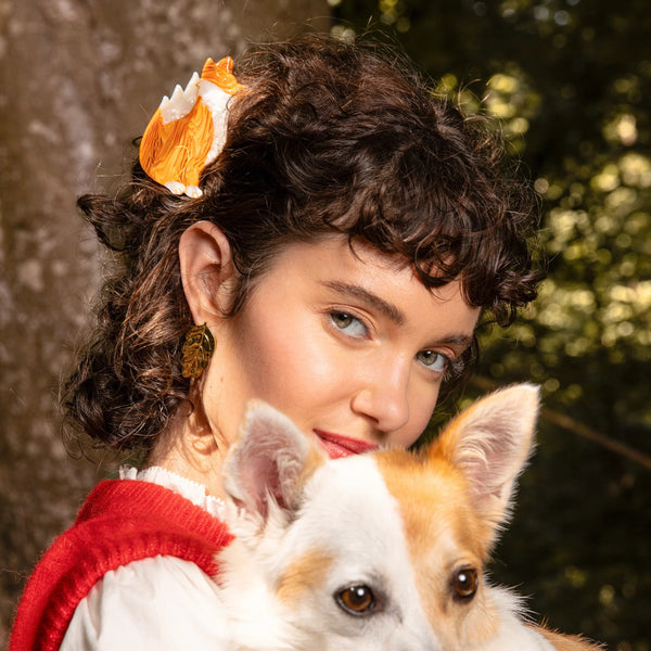 Pinza para el pelo Zorro Coucou Suzette utilizada en cabello rizado junto a un perro de pelaje blanco y naranja.