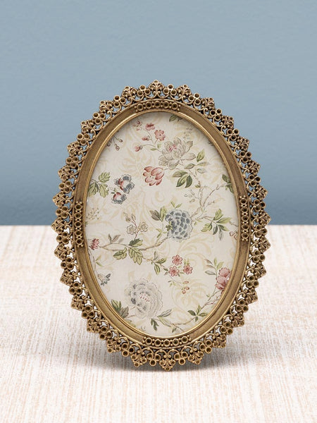 Marco de fotos ovalado dorado decorativo sobre mesa clara y fondo azul – Ideal para decoración romántica y clásica.