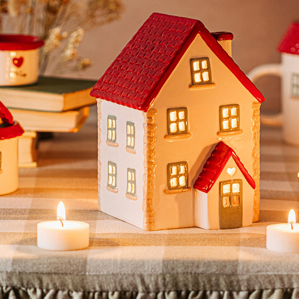 Portavelas navideño de cerámica con diseño de casita de campo roja y blanca.