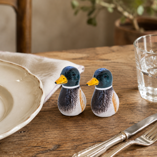 Salpimenteros con forma de pato decorando una mesa de madera junto a vajilla y cubiertos